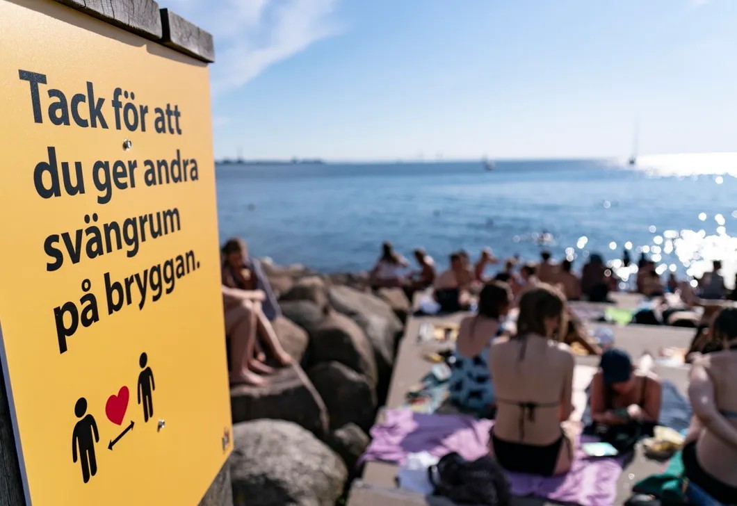 Пляж Мальмё. Люди отдыхают вблизи плаката, на котором выражена благодарность за соблюдение дистанции. Фото: EPA