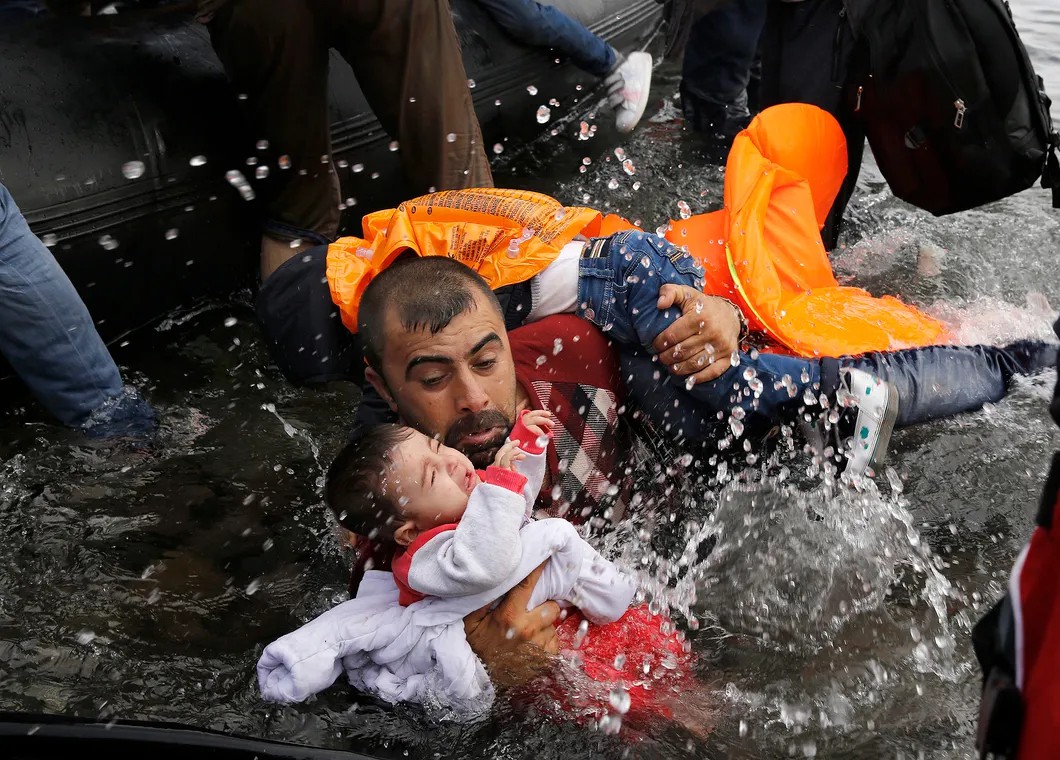 Сириец с двумя детьми пытается высадиться на сушу после переправы из Турции. Остров Лесбос, 24 сентября 2015.Фото из проекта «Дороги надежды и безнадеги». © Yannis Behrakis / Reuters