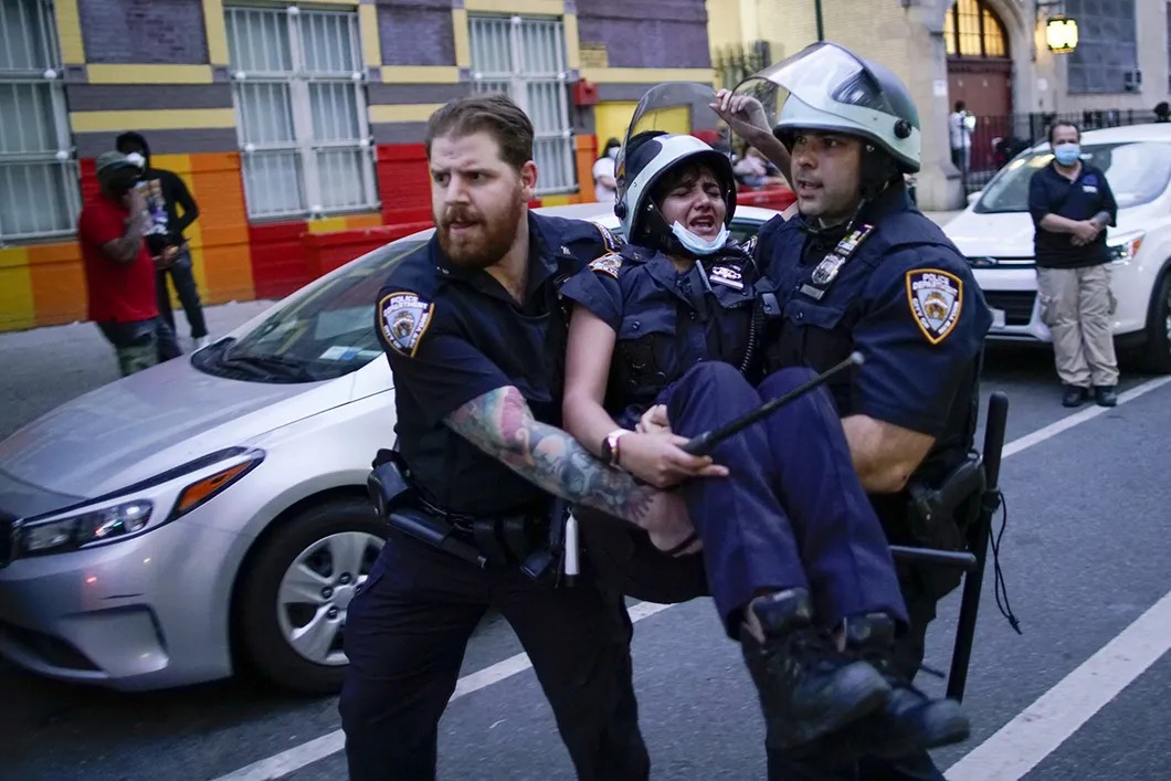 Полицейские несут коллегу, получившую травмы в результате столкновения с демонстрантами. Бруклин, Нью-Йорк, США. 30 мая 2020 г. Фото: Reuters