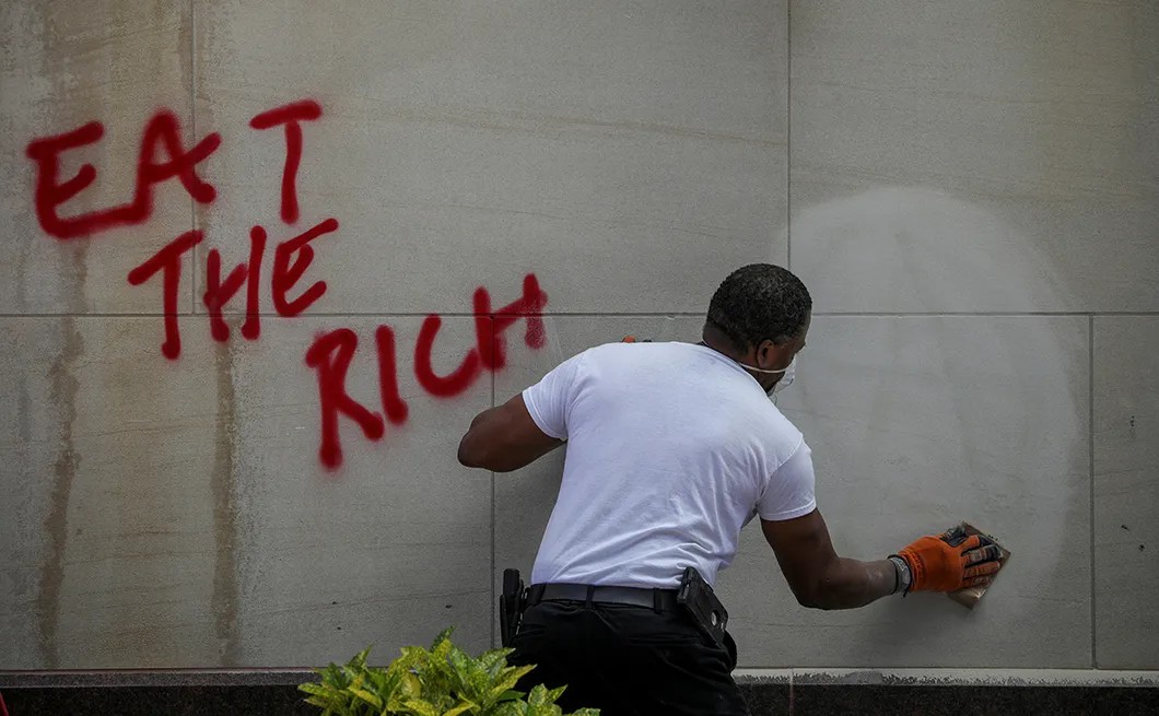 «Ешь богатых». Мужчина стирает надпись на стене возле Белого дома в Вашингтоне, Колумбия, США. 31 мая 2020 г. Фото: Reuters