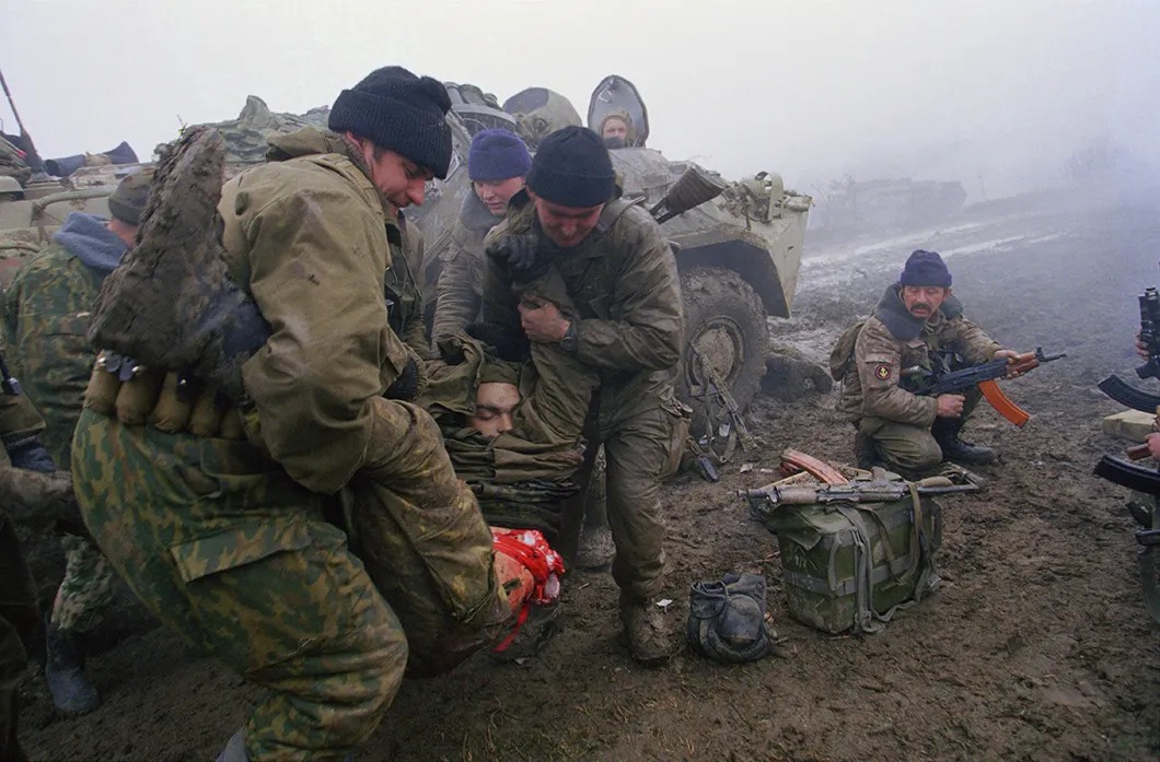 Морские пехотинцы уносят тело раненого товарища во время боя рядом с селом Центарой, Чечня. 1999 год. Фото: Юрий Козырев.