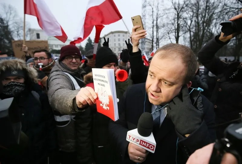 Люди передают польскую конституцию журналисту польского телевидения во время демонстрации у здания Сейма в Варшаве, Польша, 17 декабря 2017 года. Фото: EPA