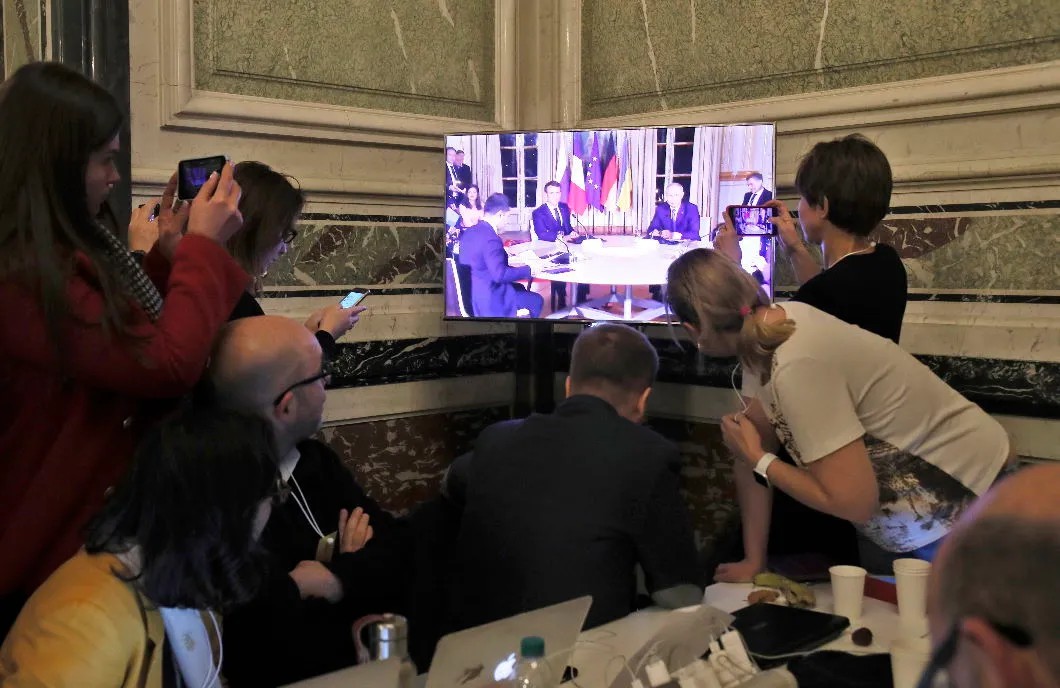 Журналисты смотрят включение из переговорной комнаты. Фото: EPA