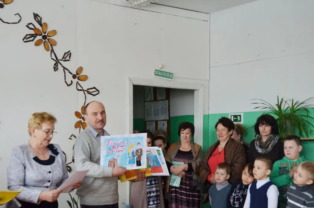 Николай Егоров показывает работы школьников — участников конкурса «Я рисую выборы», 2015 год. Фото:  «Красное знамя»