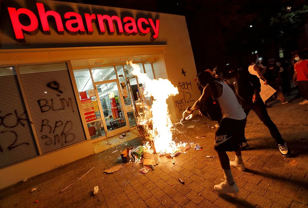 Люди поджигают предметы, похищенные из аптеки. Северная Каролина, США, 30 мая 2020 г. Фото: Reuters