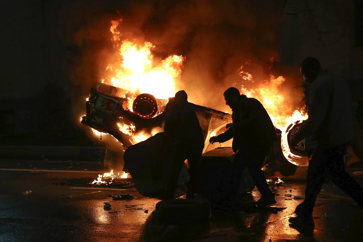 Протестующие возле горящей полицейской машины на акции против законопроекта об иностранных агентах у здания парламента Грузии. Фото: AP / TASS