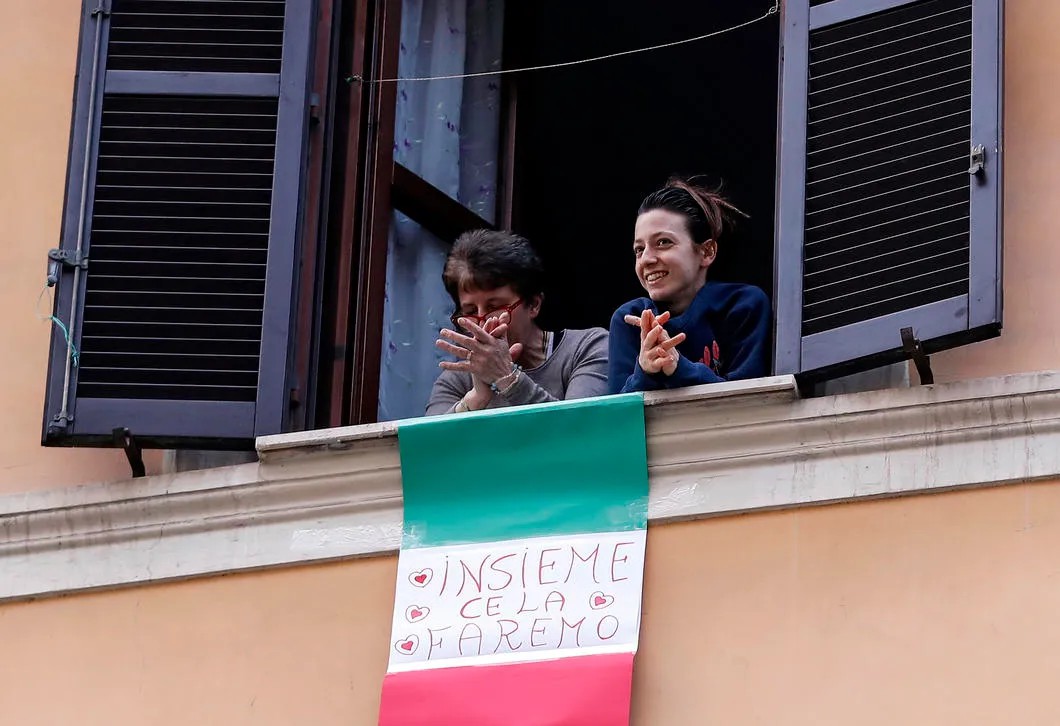 Итальянцы открывают окна, вывешивают флаги и поют в знак национальной солидарности на фоне пандемии. Рим. Фото: EPA