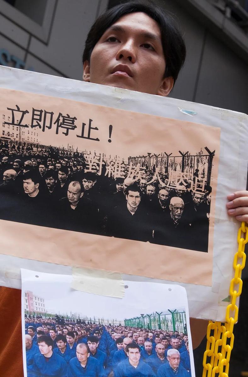 Протестующий в Гонконге держит фотографию уйгурских узников в Синьцзяне. Фото: EPA