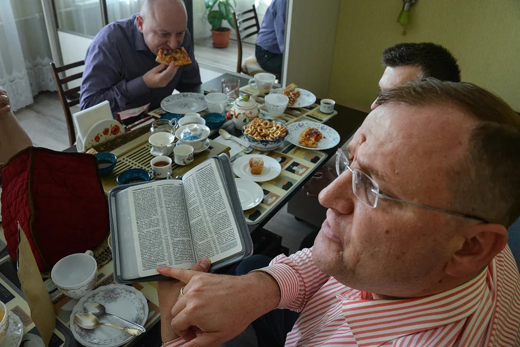 Верующие читают Библию за столом. Фото Виктория Одиссонова / «Новая»