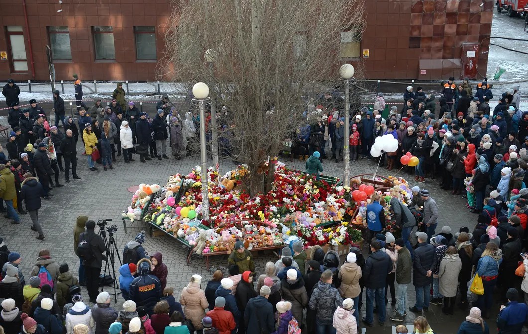 Люди несут цветы и игрушки к зданию торгового центра «Зимняя вишня». Фото: Александр Кряжев / РИА Новости