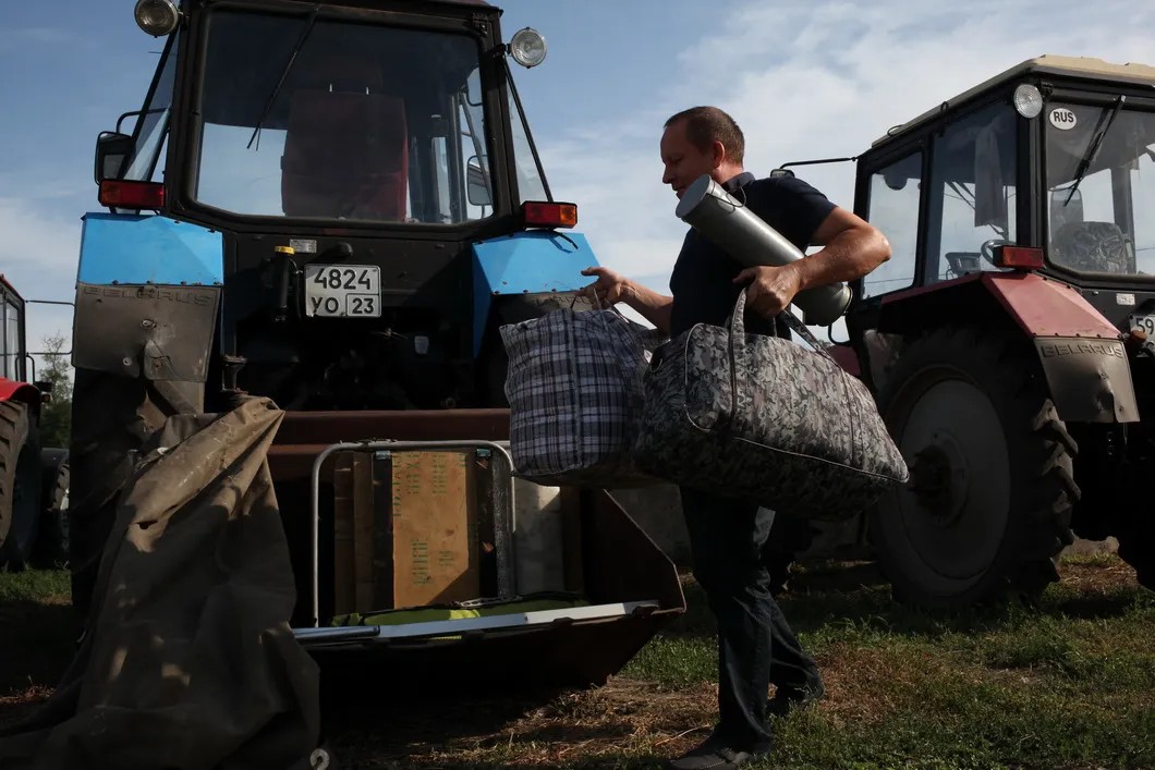 Фермер загружает дорожные вещи в ковш своего трактора. Фото: Анна Артемьева / «Новая газета»