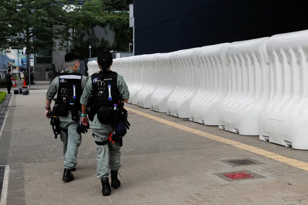 Полиция у баррикад вокруг законодательного собрания Гонконга, где в тот момент проходило второе чтение закона о гимне. Фото: Reuters