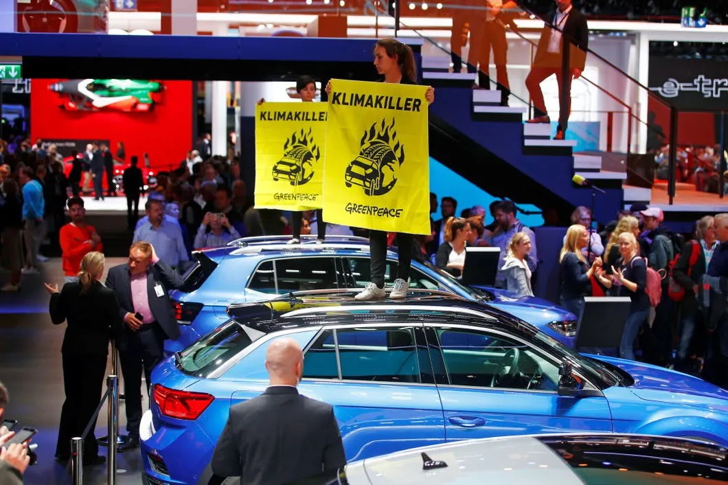 Активисты «Гринпис» устроили акцию «Убийца климата» на выставке автопрома в Германии — прямо во время выступления канцлера Меркель. Фото: EPA