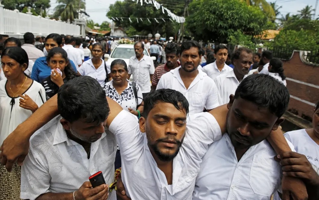 Участник массовых похорон жертв серии террористических атак на объекты в Негомбо, Шри-Ланка. Среди жертв взрывов в католическом соборе много детей. Два дня после трагедии. Фото: Reuters