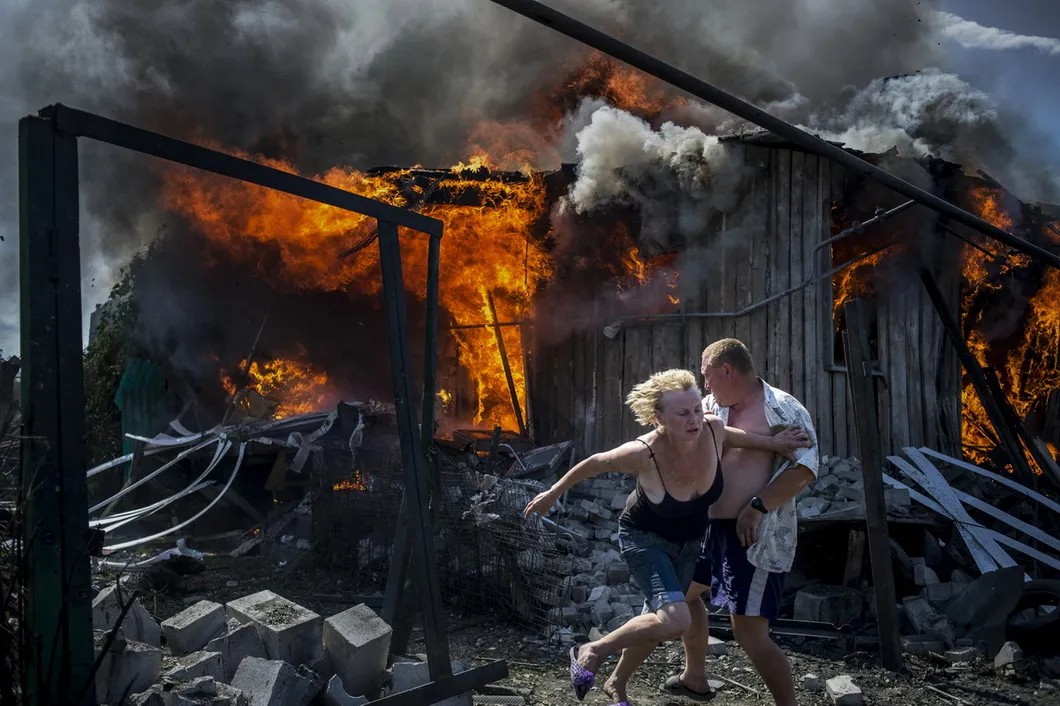 2 июля 2014 года. Мирные жители выбегают из дома, разрушенного авиаударом в станице Луганской. Фото: Валерий Мельников