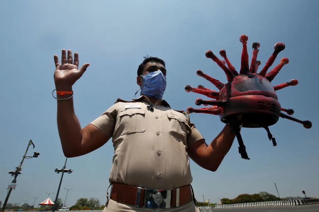 Офицер полиции в Индии со шлемом, стилизованном под частицу вируса, на дежурстве во время 21-дневного локдауна. Фото: Reuters