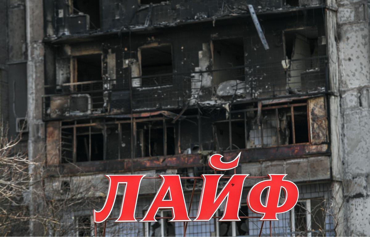 Вывеска магазина «Лайф» на фоне разрушенного и сгоревшего дома на окраине Мариуполя. Фото: РИА Новости