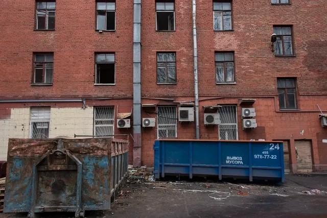 Гостиница «Алтай». За двумя закрытыми окнами на втором этаже (над синим контейнером) все еще живут люди. Фото: Виктория Одиссонова / «Новая газета»