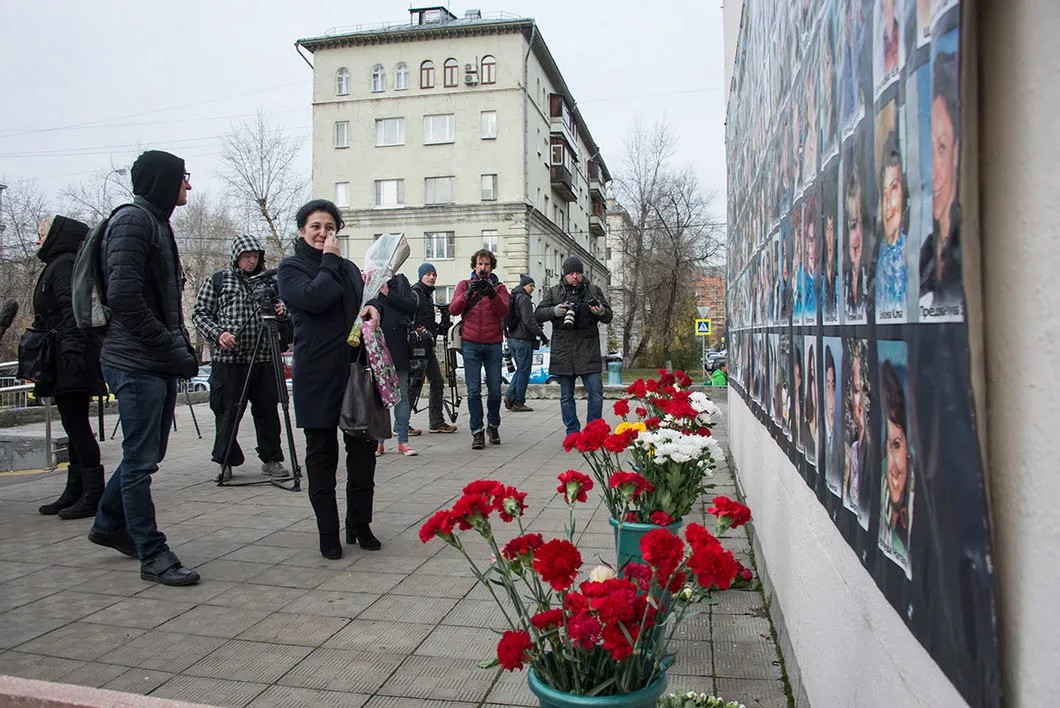Эльвира Туаева («Матери Беслана») возлагает цветы к плакату с фотографиями погибших. Фото: Виктория Одиссонова / «Новая газета»