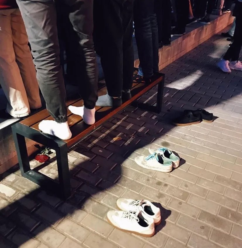 Молодежь Беларуси во время протестного митинга стоит на уличной скамейке, сняв ботинки, чтобы ее не запачкать. Фото: соцсети