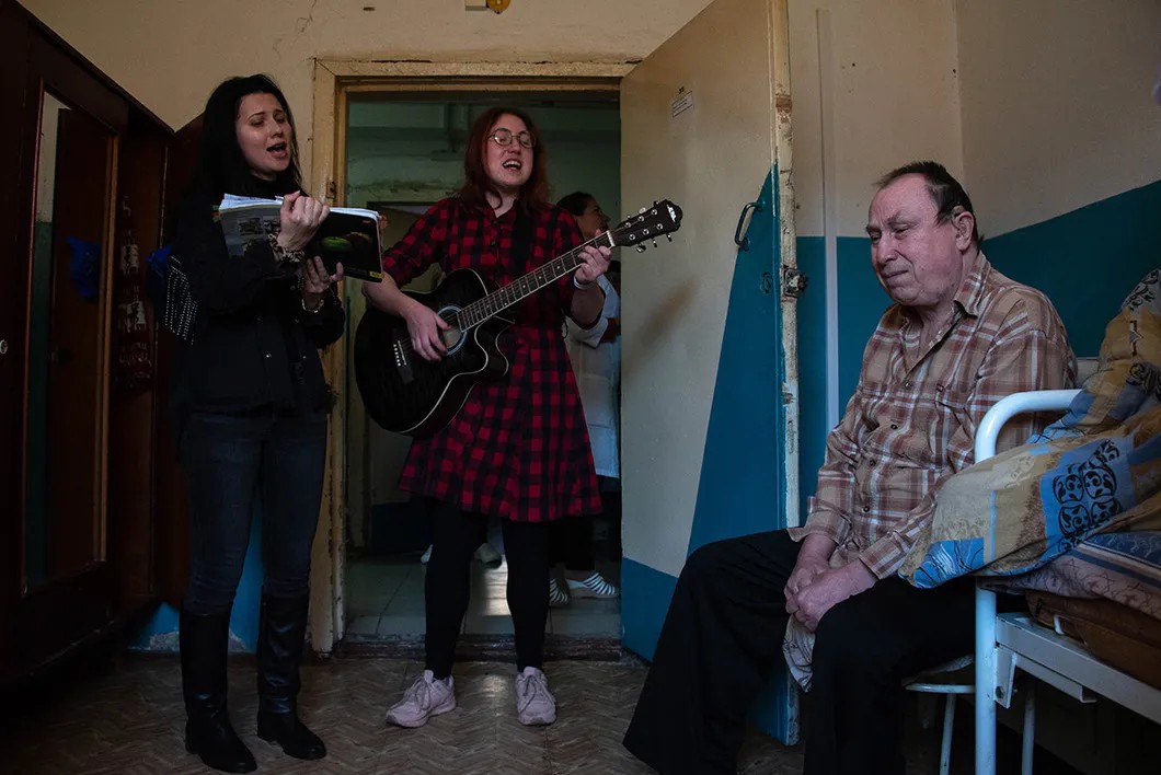 Волонтеры поют под гитару в доме престарелых. Фото: Виктория Одиссонова «Новая»