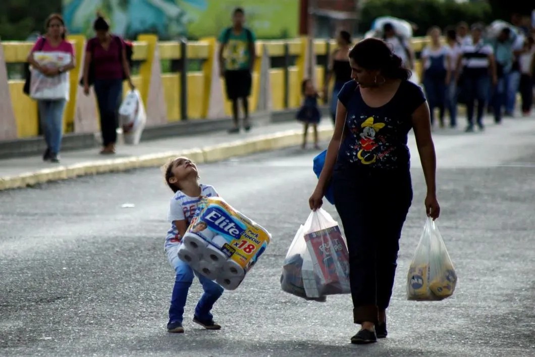 11 июля 2017 года. Граница Венесуэлы и Колумбии. Девочка помогает матери нести покупки первой необходимости, Фото: Reuters