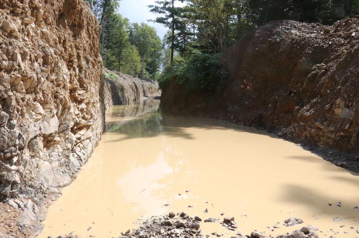 Еще осенью эта геологическая канава стояла заросшая. Сейчас шурф глубиной 220 см заполнен грязной водой. Фото: Валерия Федоренко / «Новая газета»