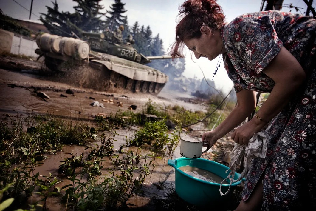 Осетинская женщина берет воду из грязного уличного водостока. Цхинвал. Фото: Юрий Козырев / «Новая»
