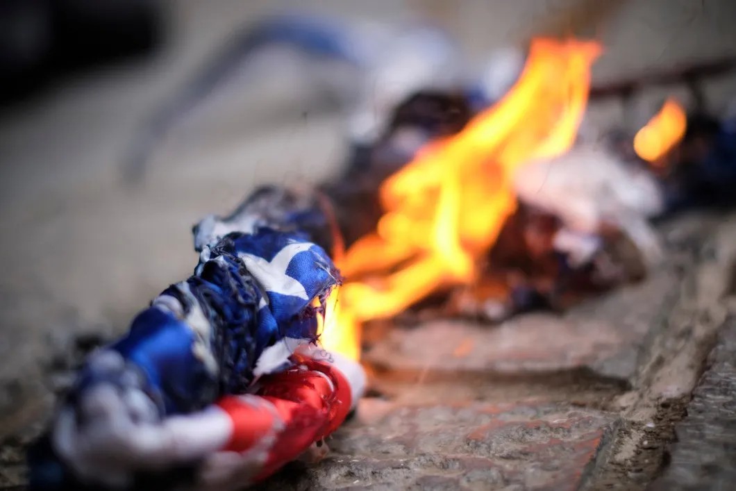 Протестующие сжигают флаги США во время акции против убийства известного иранского ученого-ядерщика и члена Корпуса стражей исламской революции Мохсена Фахризаде Махабади у здания Министерства иностранных дел. Фото: NurPhoto / Getty Images