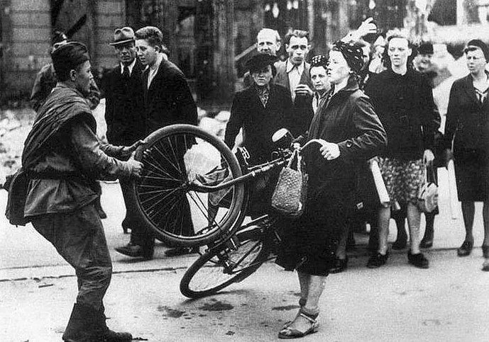 Советский солдат отбирает велосипед у немецкой женщины. Берлин, 1945