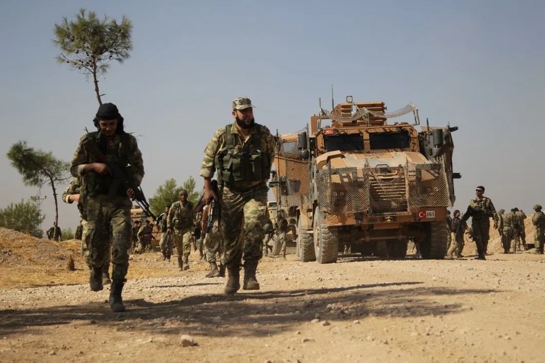 Бойцы третьего корпуса ССА стоят перед турецкой военной техникой после захвата деревни Аль-Ябиса, которая находится к западу от города Эт-Телль-эль-Абьяд. Фото: источник, специально для «Новой газеты».
