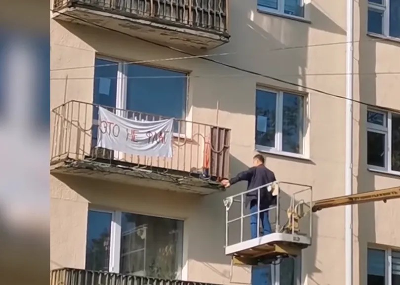 Коммунальщики с подъемником снимают простыню с надписью «Это не флаг». Скриншот видео TUT.BY
