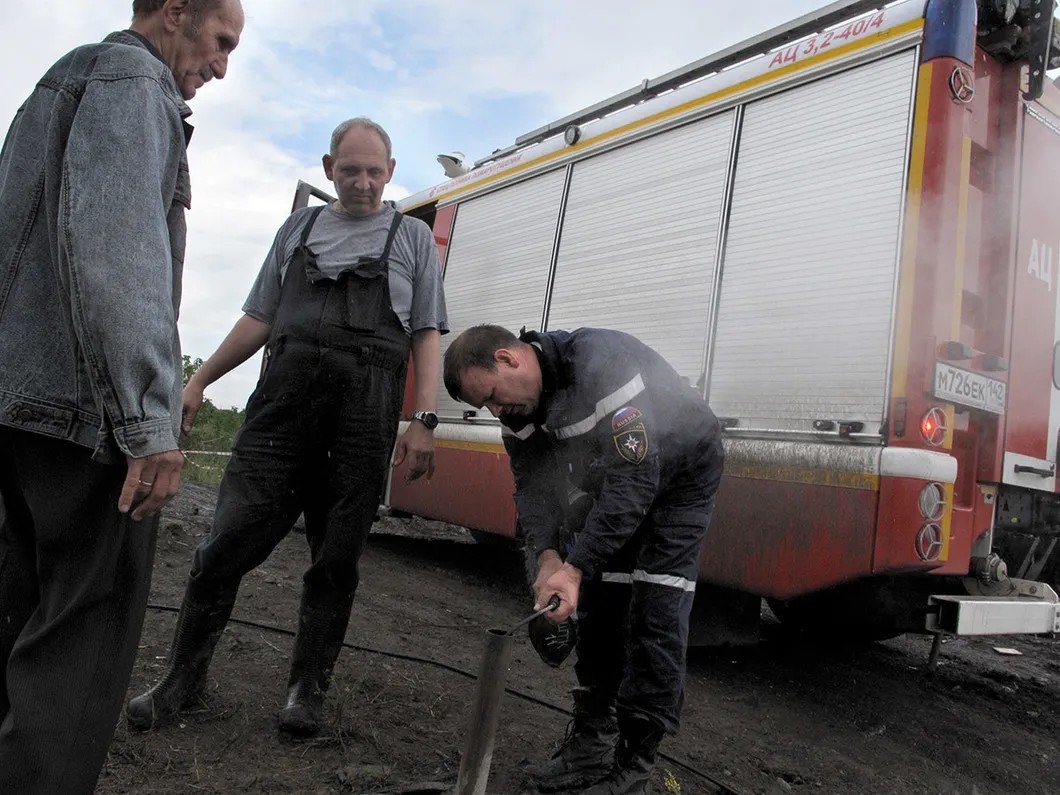 Спасатель набирает дым из скважины для анализа. Фото: Никита Гирин / «Новая газета»