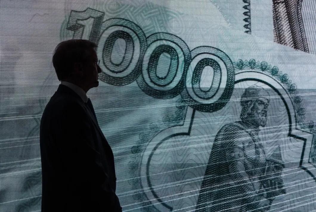 Герман Греф на фоне изображения купюры номиналом 1000 рублей. Фото: РИА Новости