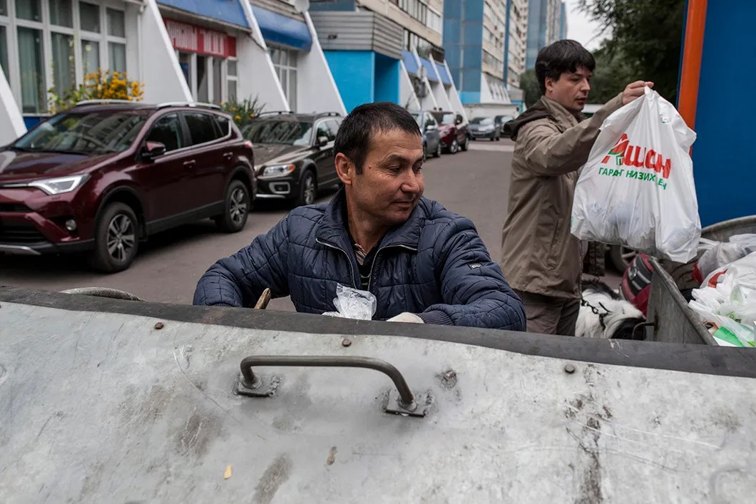 Мухиддин разбирает содержимое мусорного контейнера. Фото: Влад Докшин / «Новая»