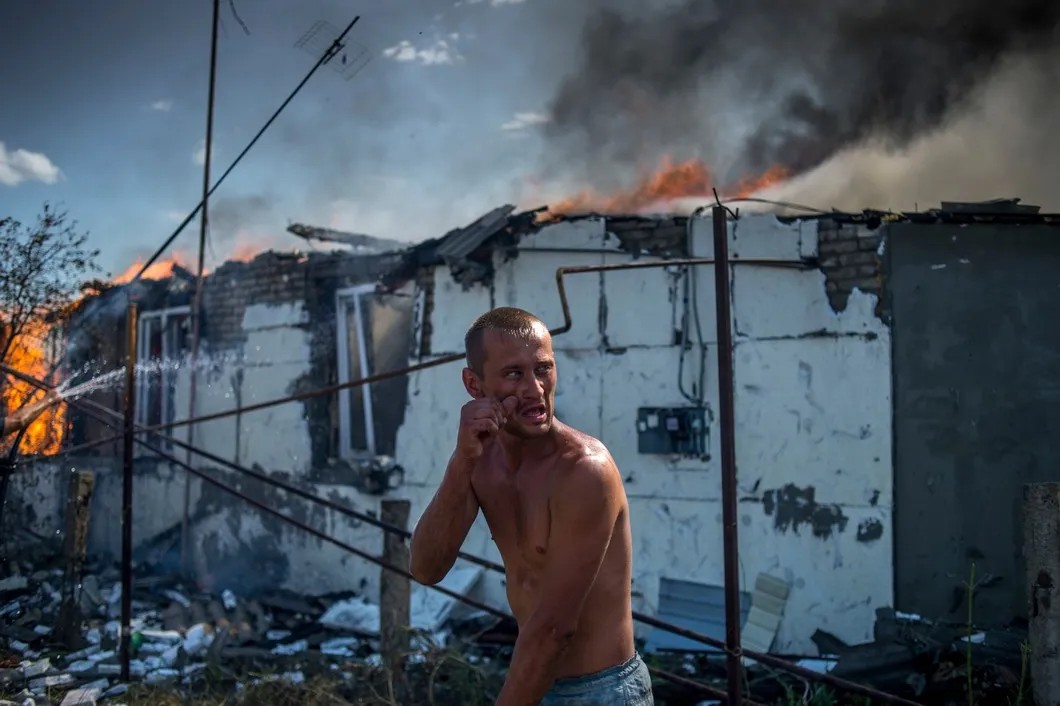 Местный житель во время тушения пожара в одном из домов в станице Луганская, подвергшейся авиационному удару. Фото: РИА Новости