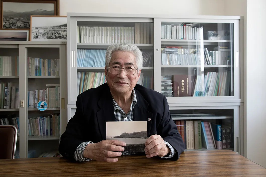 Хироси Токуно с архивной фотографией его родного острова. Фото: Анна Артемьева / «Новая»