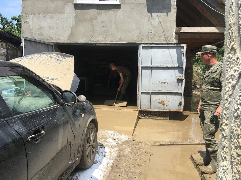 Военные специальными «швабрами» выгоняют воду и ил из гаража. Фото: Анастасия Смирнова