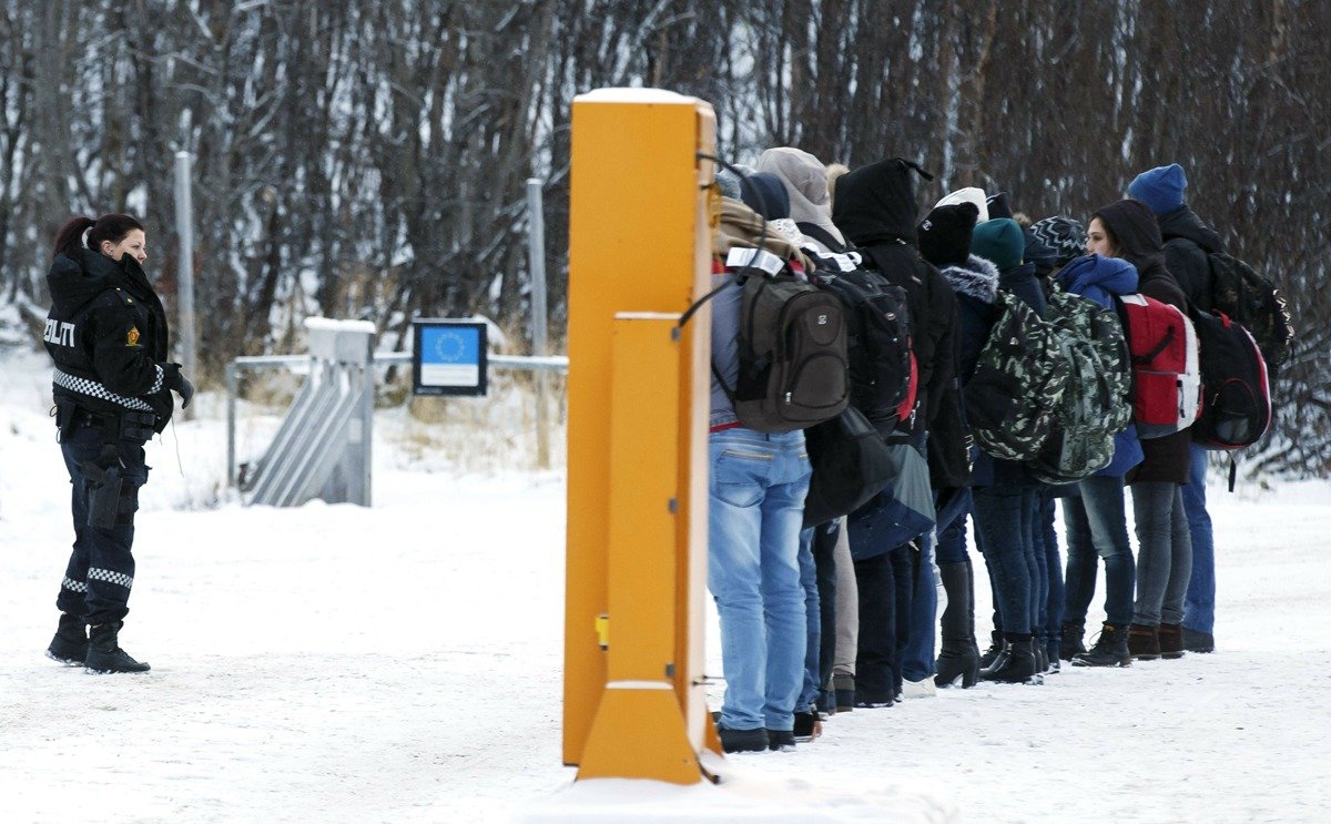 Мигранты получают инструкции от норвежского полицейского на пограничном пункте Стурског недалеко от Киркенеса. Фото: AFP / EAST NEWS