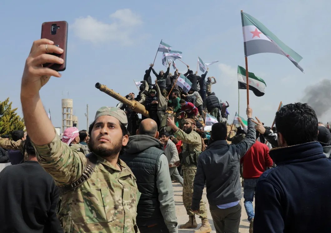 Люди с флагами сирийской оппозиции митингуют против соглашения о совместном турецко-российском патрулировании трассы М4. Идлиб, Сирия. 15 марта 2020 года. Фото: Reuters