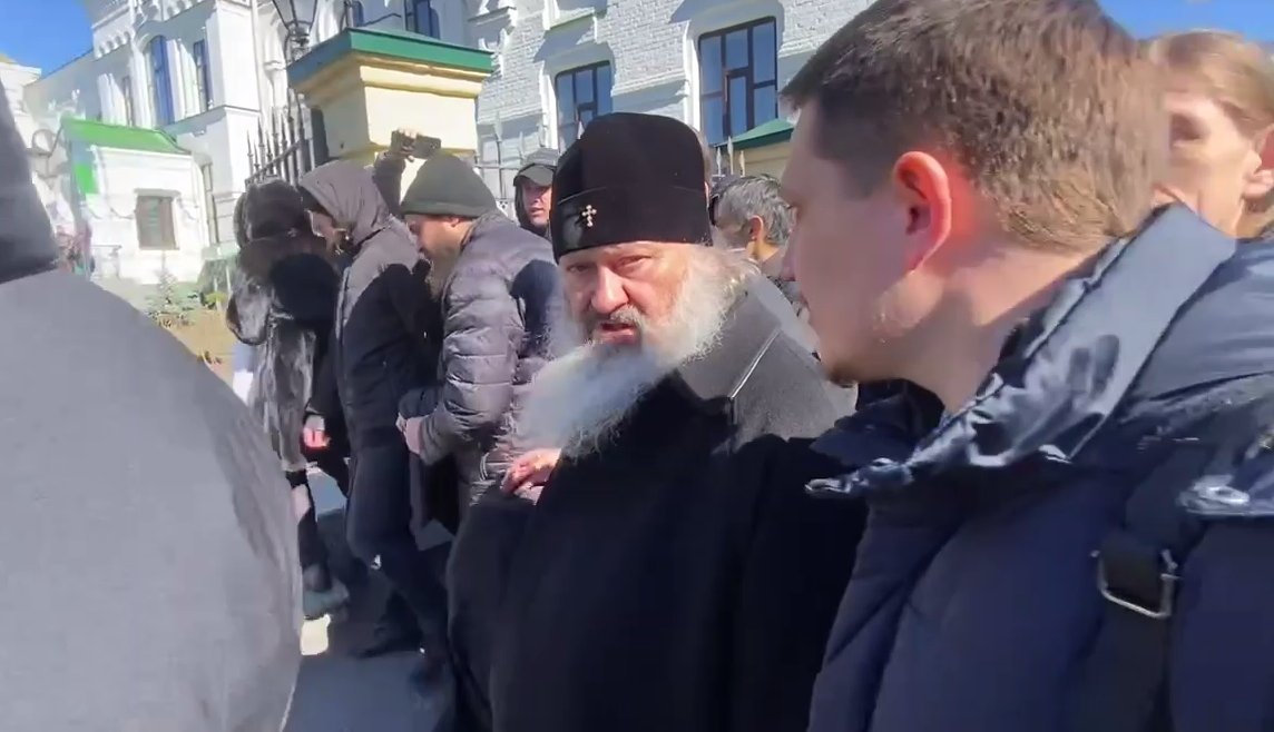 Настоятель митрополит Лебедь в окружении братии перемещается по территории Киево-Печерской лавры и отбивается от журналистов. Кадр от 30 марта 2023 года