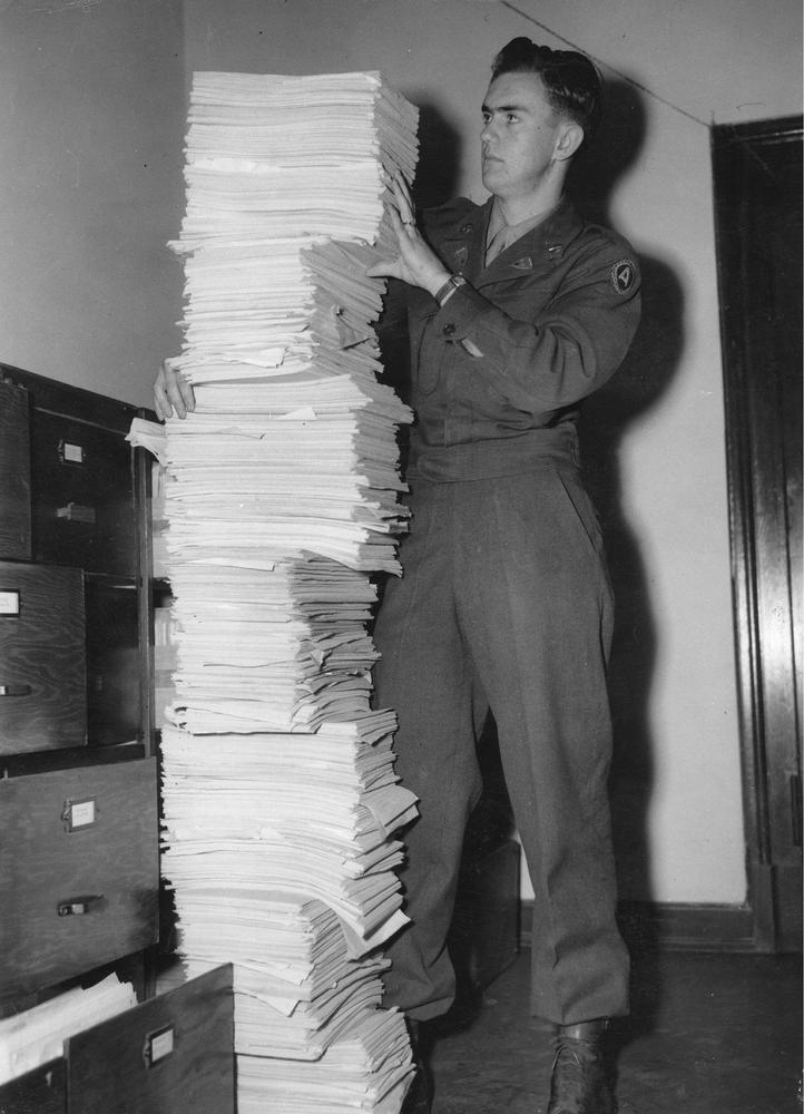 Американский солдат Герберт Бо держит стопку стенограмм, представляющих небольшую часть доказательств для обвинения по Нюрнберскому процессу, 1946 год. Фото: Imagno / Getty Images