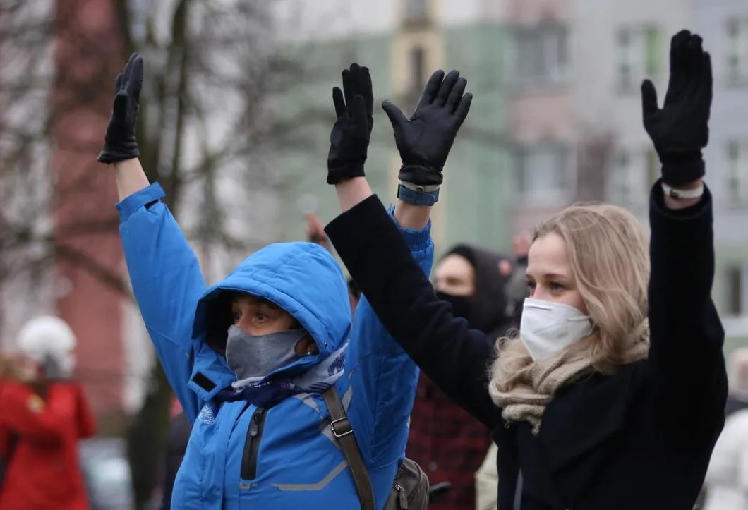 Белорусы поднимают руки вверх перед силовиками на мирных акциях протеста, которые длятся уже больше 100 дней. Фото: EPA