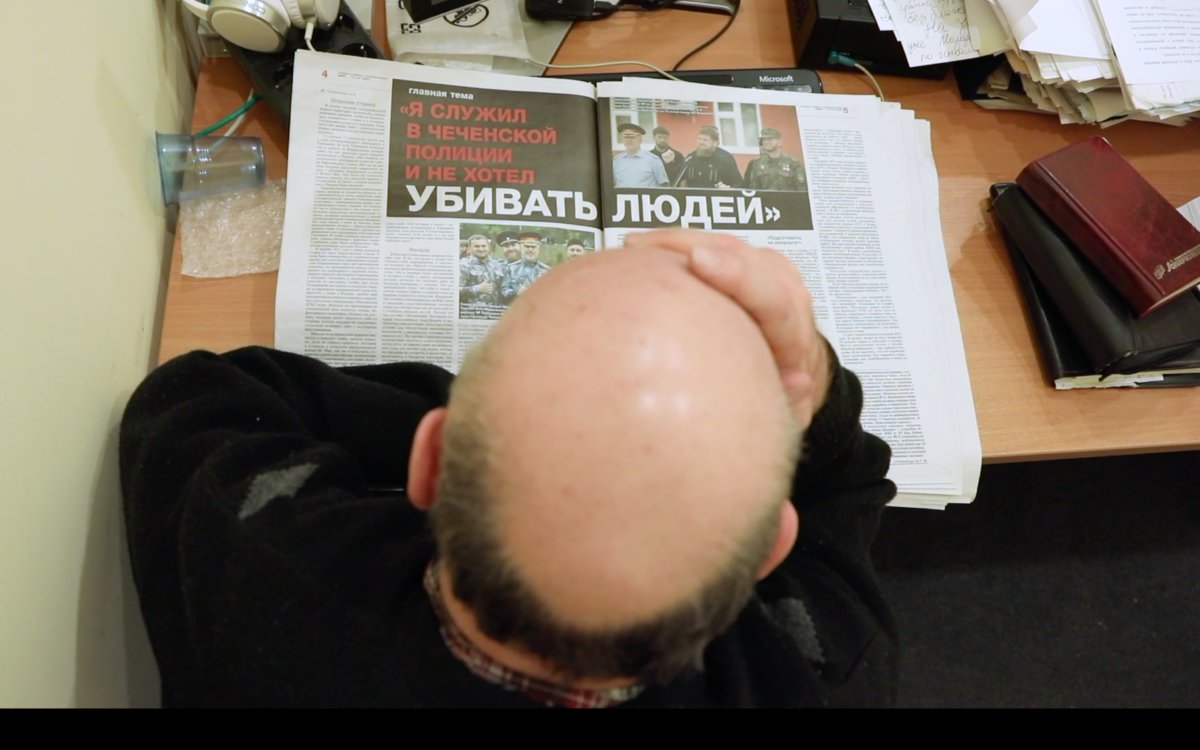 Вячеслав Измайлов читает статью Елены Милашиной о внесудебных казнях в сегодняшней Чечне. Кадр из фильма «В лысого не стрелять!»