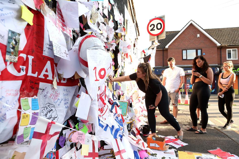 Люди украшают плакатами и флагами граффити с изображением футболиста Маркуса Рашфорда. Фото: Charlotte Tattersall / Getty Images