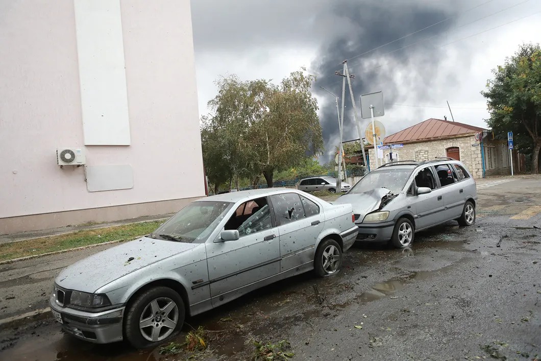 Машины, пострадавшие от осколков, на фоне дыма горящей электростанции. Фото: Павел Волков / специально для «Новой»